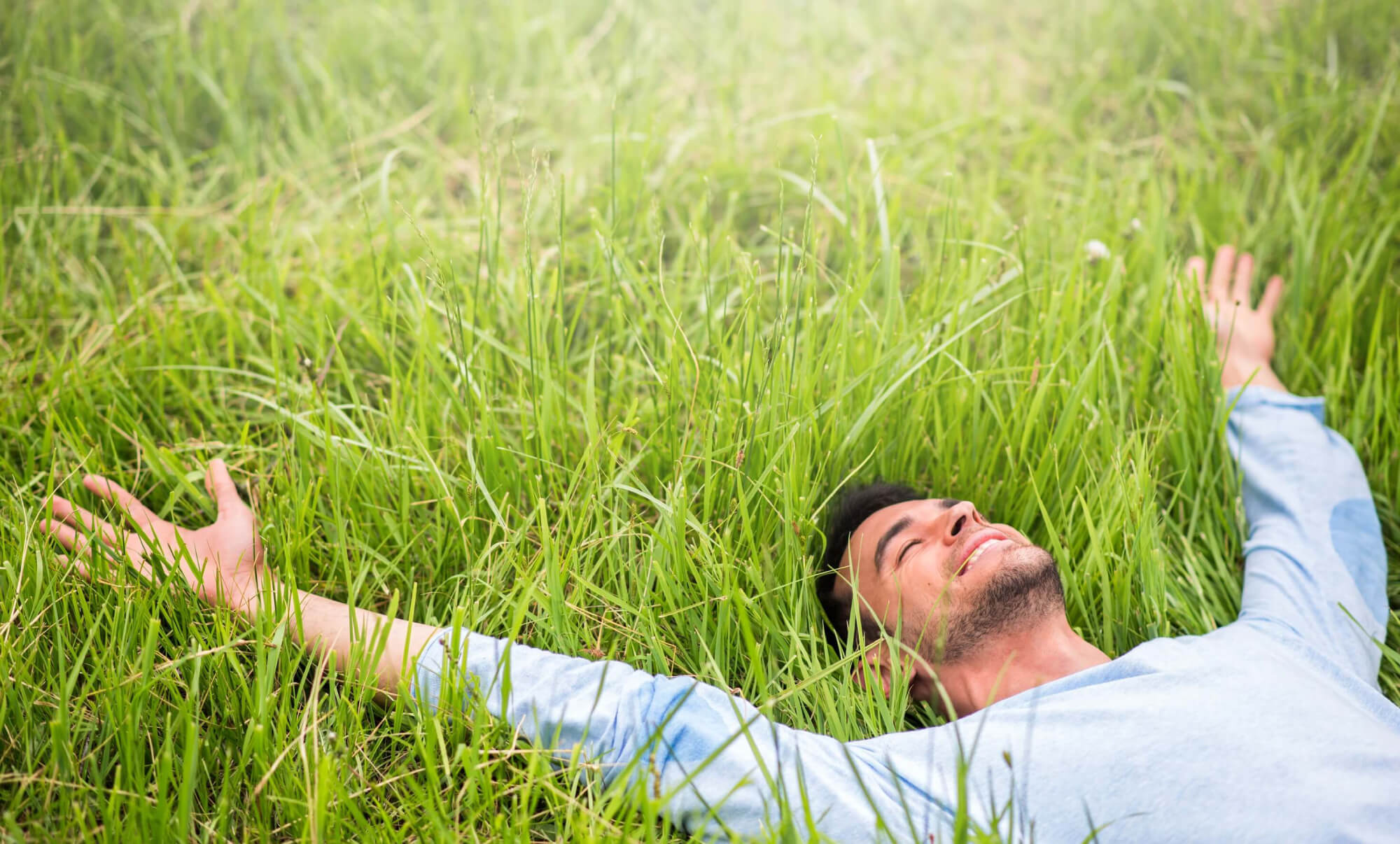 A man happily sleeping on the grass